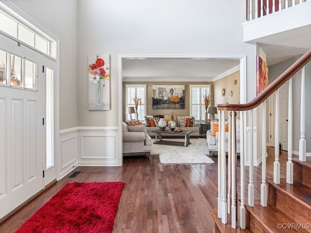 entryway featuring hardwood / wood-style floors, crown molding, and a high ceiling