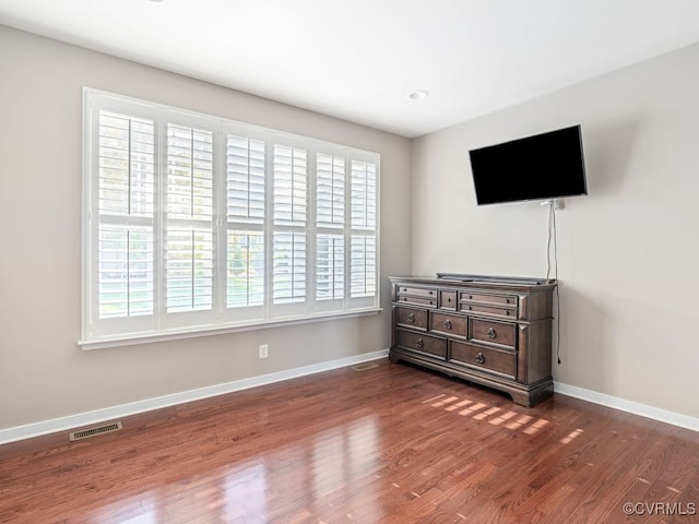 bedroom featuring multiple windows and dark hardwood / wood-style flooring