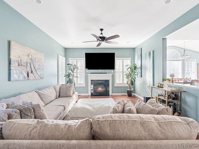 living room with ceiling fan, vaulted ceiling, and light wood-type flooring