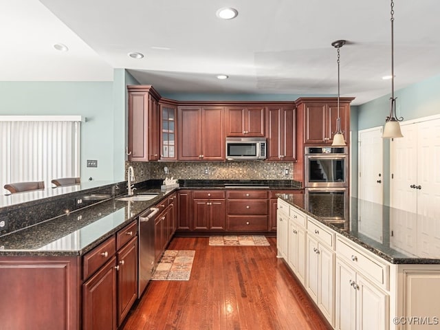 kitchen with pendant lighting, cream cabinets, sink, dark hardwood / wood-style floors, and appliances with stainless steel finishes