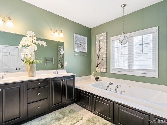 bathroom with a washtub, vanity, and tile patterned floors