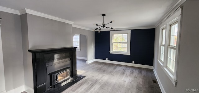 unfurnished living room with a wood stove, a notable chandelier, ornamental molding, and wood-type flooring