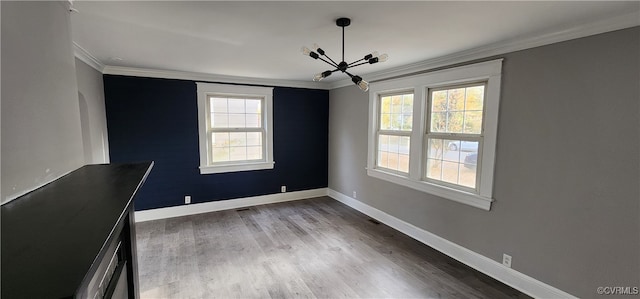 spare room with a wealth of natural light, crown molding, and wood-type flooring