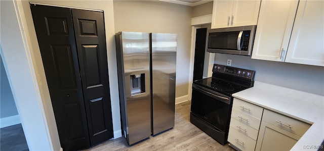 kitchen with white cabinetry, light hardwood / wood-style floors, stainless steel appliances, and crown molding