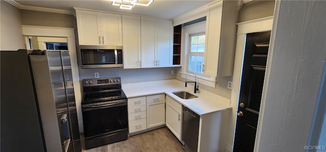 kitchen featuring sink, white cabinetry, stainless steel appliances, crown molding, and light hardwood / wood-style flooring