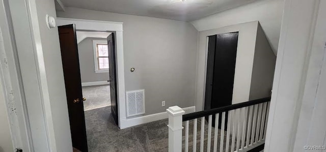 hall featuring dark colored carpet