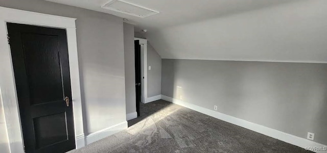 bonus room with dark carpet and vaulted ceiling