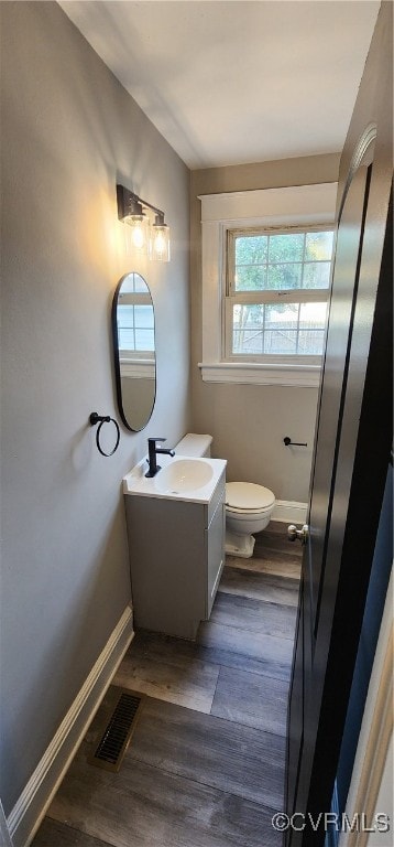 bathroom featuring vanity, toilet, hardwood / wood-style flooring, and a wealth of natural light