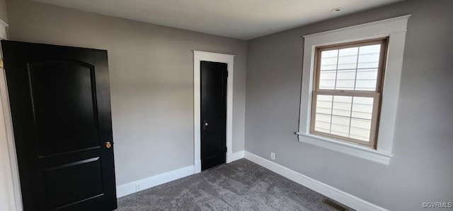 unfurnished bedroom with dark colored carpet