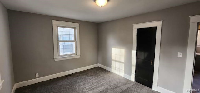 unfurnished room featuring dark colored carpet