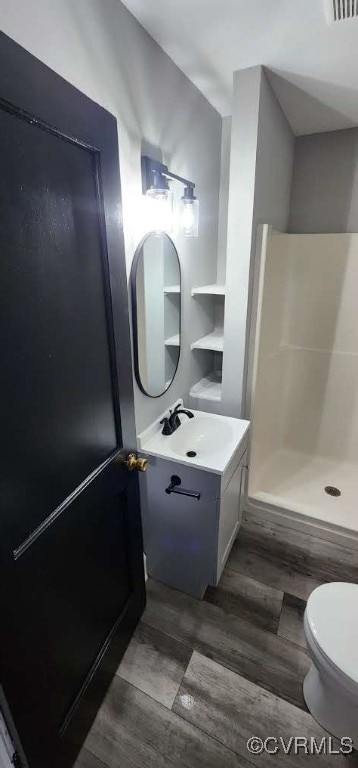 bathroom featuring vanity, walk in shower, toilet, and hardwood / wood-style flooring