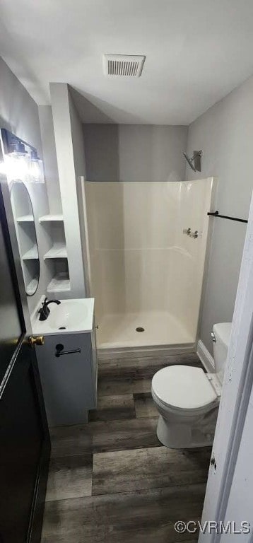 bathroom featuring vanity, walk in shower, toilet, and wood-type flooring