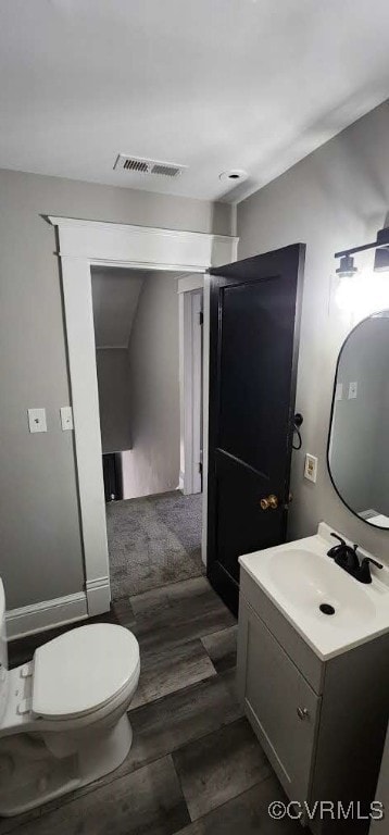 bathroom featuring toilet, lofted ceiling, vanity, and wood-type flooring