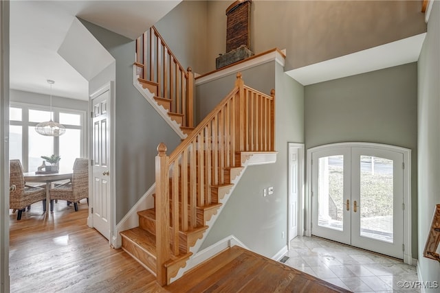 foyer featuring light hardwood / wood-style floors, french doors, a healthy amount of sunlight, and an inviting chandelier