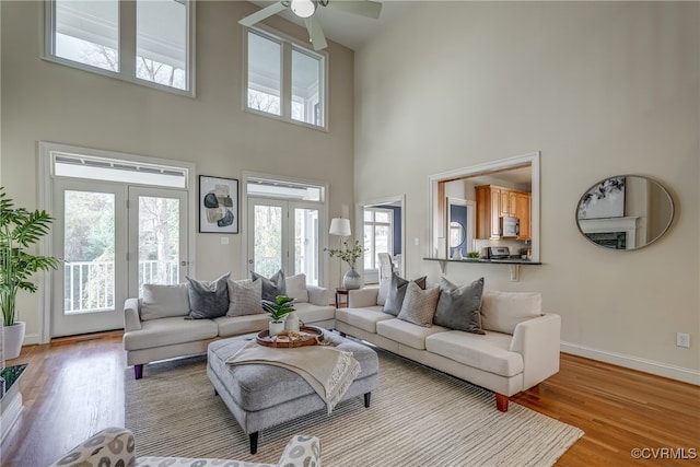 living room with a high ceiling, light hardwood / wood-style flooring, a wealth of natural light, and ceiling fan