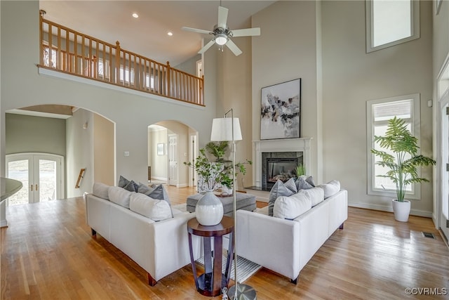 living room with light wood-type flooring, a towering ceiling, and plenty of natural light