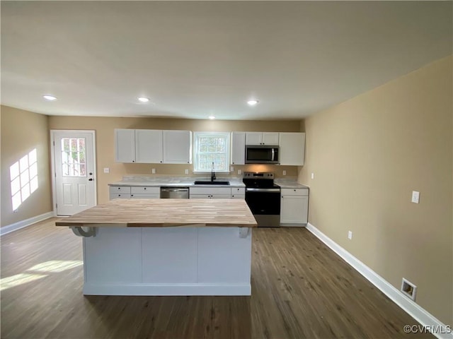 kitchen with sink, dark hardwood / wood-style floors, white cabinetry, butcher block counters, and stainless steel appliances