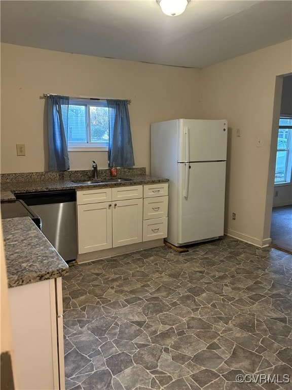 kitchen with white fridge, sink, white cabinets, dishwasher, and dark stone countertops