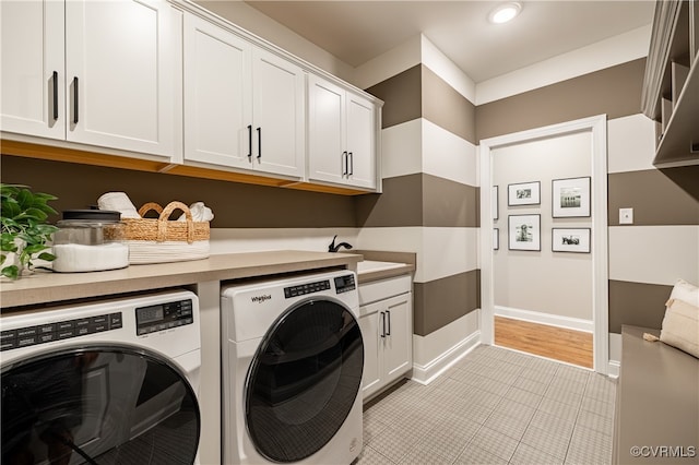 laundry room featuring cabinets, sink, washer and dryer, and light tile patterned flooring