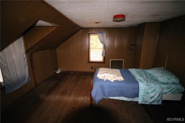 bedroom with wooden walls, vaulted ceiling, and dark hardwood / wood-style floors