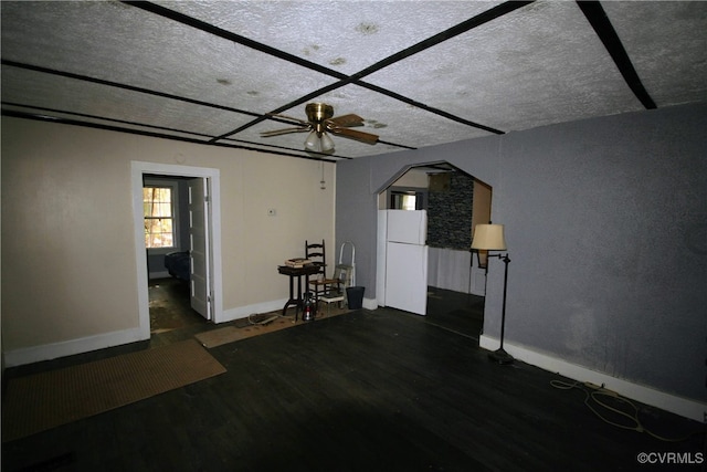 unfurnished living room featuring ceiling fan, dark hardwood / wood-style floors, and a textured ceiling