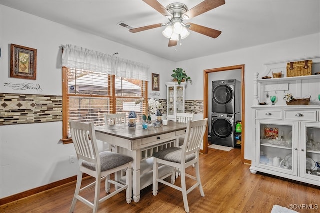 dining area with ceiling fan, stacked washer and dryer, and light hardwood / wood-style flooring