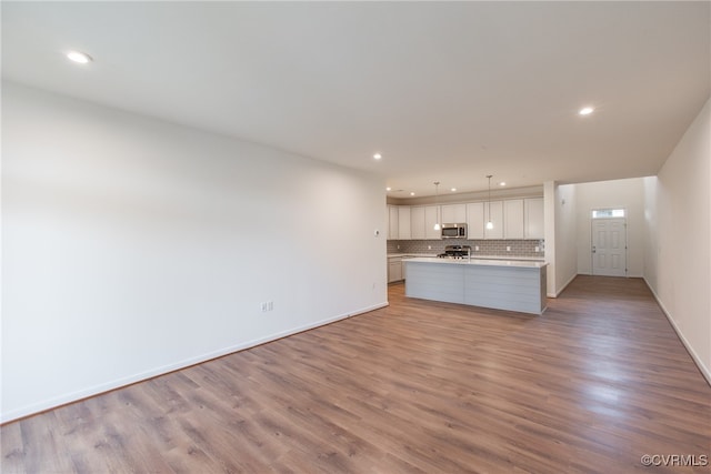 unfurnished living room featuring light wood-type flooring, baseboards, and recessed lighting