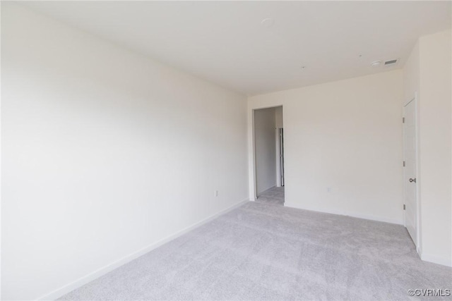 spare room with baseboards, visible vents, and light colored carpet
