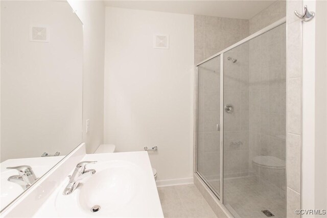 bathroom featuring toilet, tile patterned flooring, a stall shower, and a sink