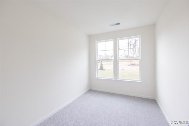 empty room with a healthy amount of sunlight, light colored carpet, baseboards, and visible vents