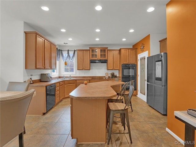 kitchen with black appliances, a breakfast bar area, a kitchen island, and light tile patterned floors