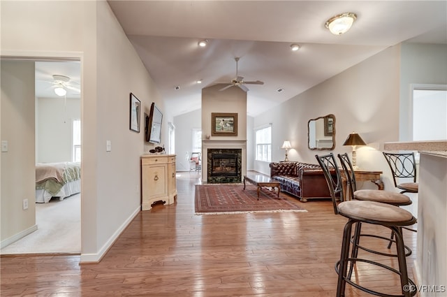 living room with lofted ceiling, hardwood / wood-style flooring, ceiling fan, and a high end fireplace