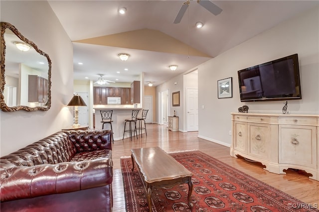 living room with light hardwood / wood-style floors, ceiling fan, and vaulted ceiling