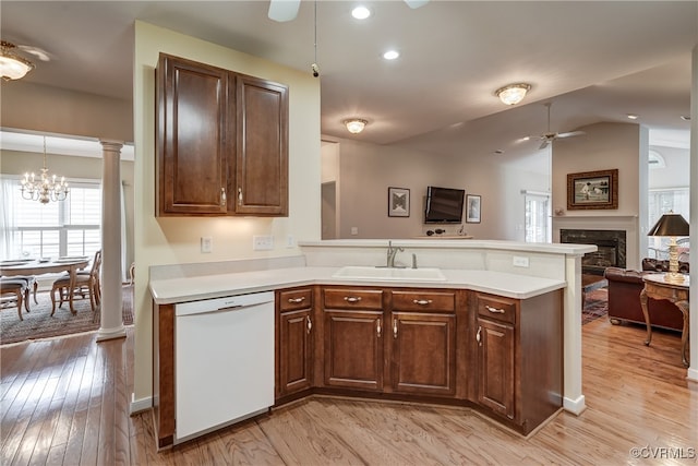 kitchen with light hardwood / wood-style floors, dishwasher, kitchen peninsula, hanging light fixtures, and sink