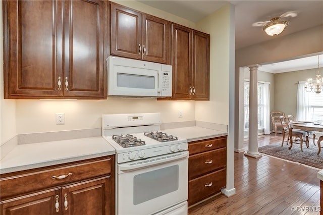 kitchen with ornate columns, a notable chandelier, pendant lighting, light wood-type flooring, and white appliances