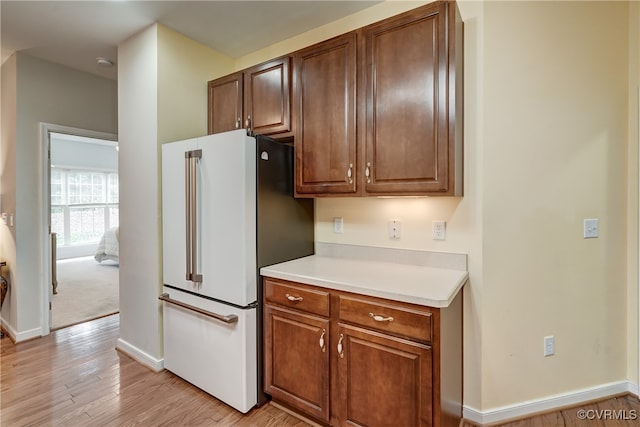 kitchen with high end fridge and light hardwood / wood-style flooring