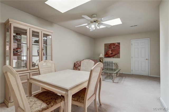 carpeted dining space with ceiling fan and a skylight