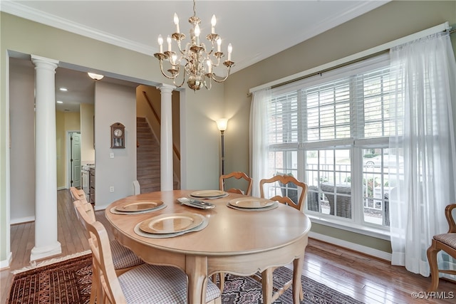 dining space featuring ornate columns, hardwood / wood-style floors, a notable chandelier, and crown molding