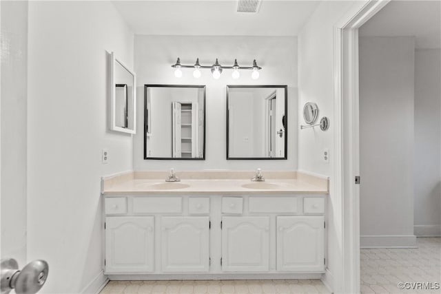 bathroom featuring double vanity, visible vents, baseboards, and a sink