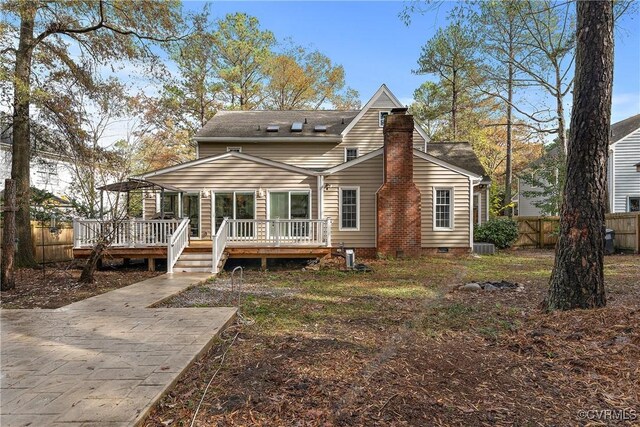 rear view of property with a wooden deck, fence, a chimney, and crawl space