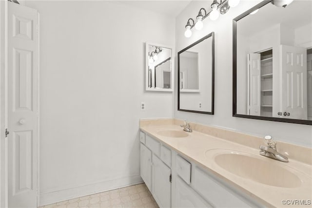 bathroom featuring a sink, baseboards, double vanity, and tile patterned floors