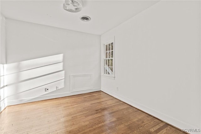 unfurnished room with wood finished floors, visible vents, and baseboards