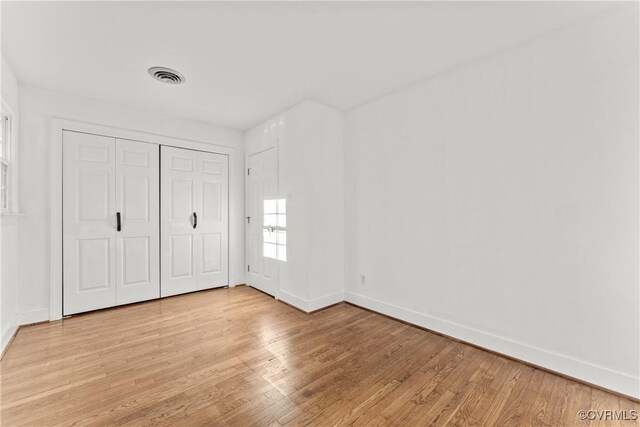 unfurnished bedroom with a closet, visible vents, light wood-style flooring, and baseboards