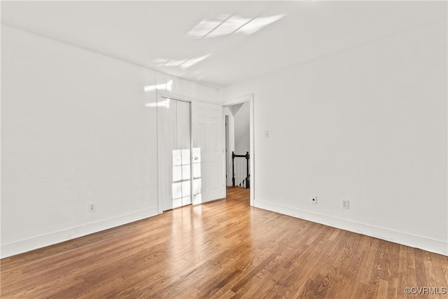 spare room with baseboards and wood finished floors