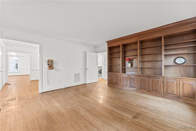 unfurnished room featuring baseboards, visible vents, washer / clothes dryer, ornamental molding, and light wood-style floors