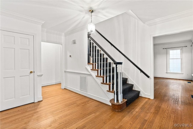 stairs featuring visible vents, hardwood / wood-style flooring, and ornamental molding