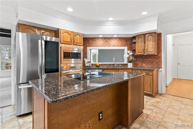 kitchen featuring a kitchen island, ornamental molding, brown cabinets, appliances with stainless steel finishes, and a sink