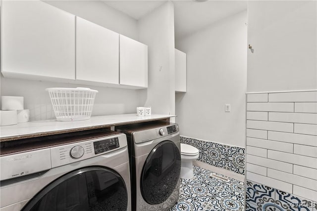 clothes washing area with washing machine and clothes dryer, cabinet space, and tile patterned floors