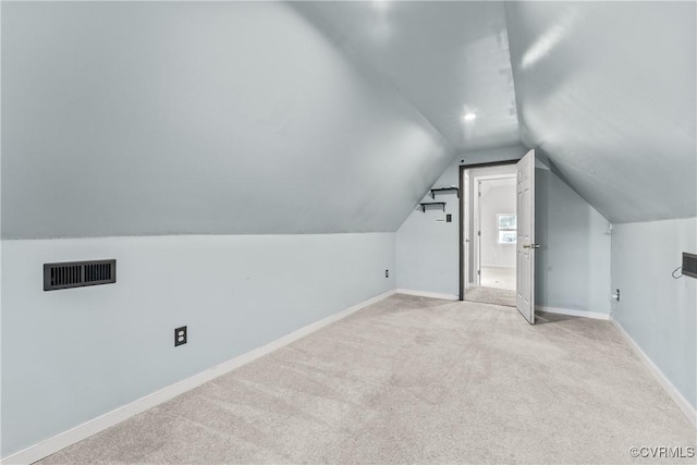 additional living space featuring light colored carpet, lofted ceiling, baseboards, and visible vents