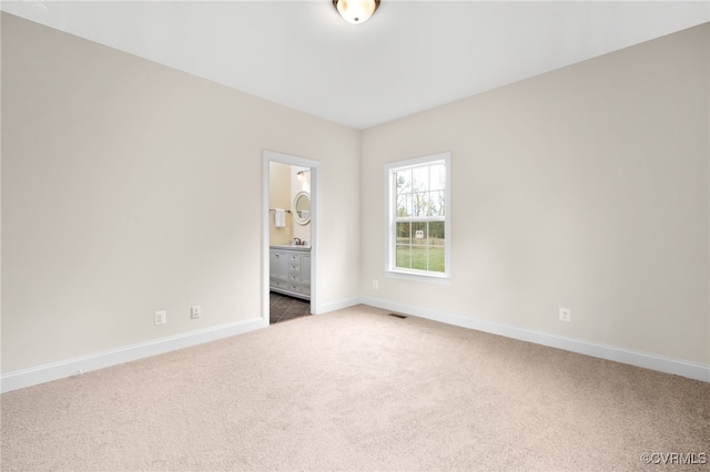 unfurnished bedroom featuring carpet flooring, ensuite bathroom, and sink